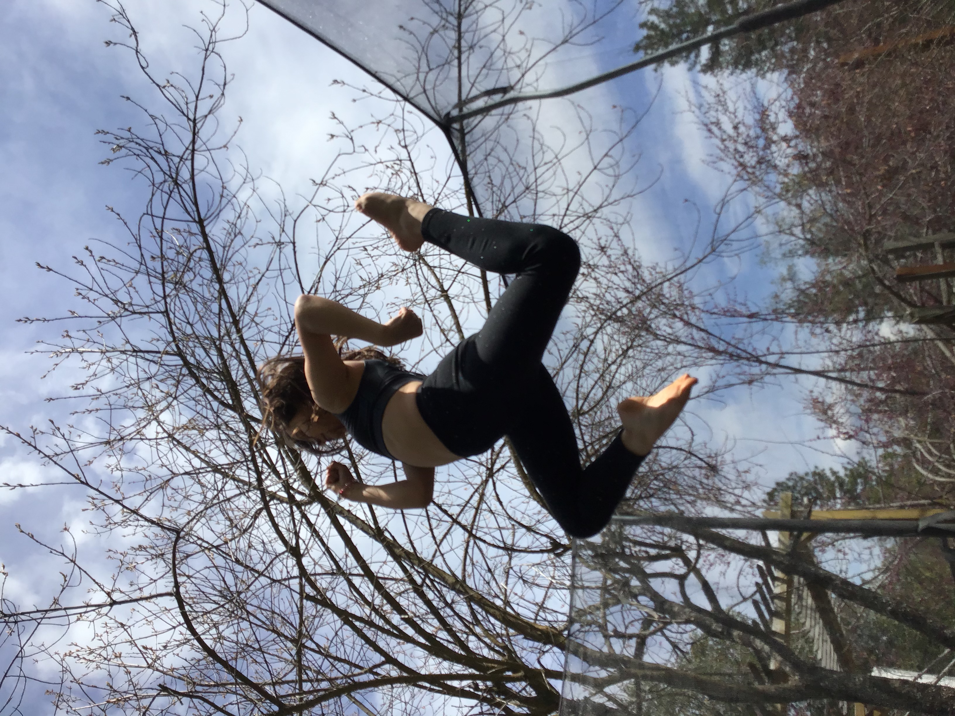 13 Mikenna Seymour tmbtp image Photograph of young girl jumping on a trampoline. She is in profile and her feet are pointed in a dynamic pose.