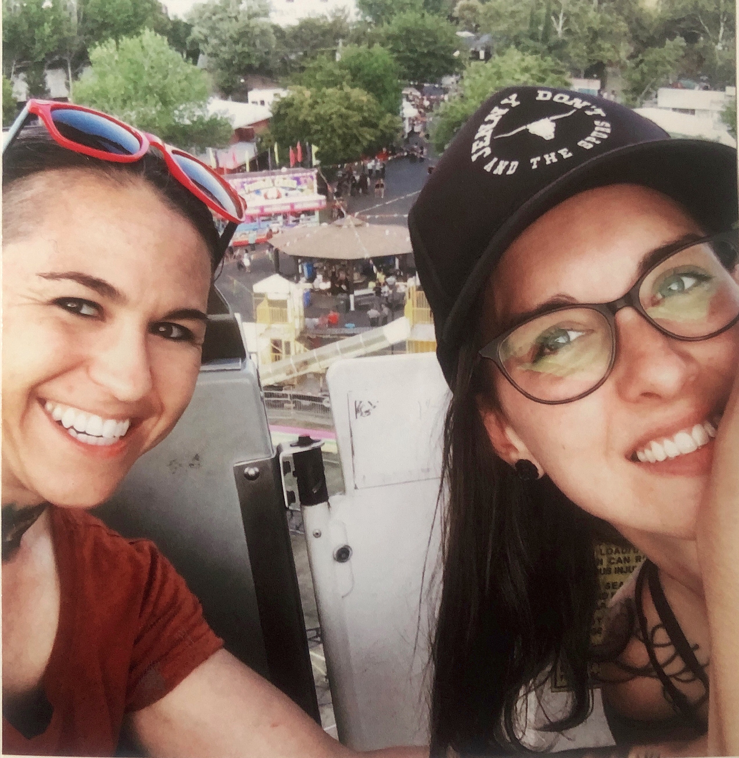 16 Clay River and Rose Fluharty tmbtp image Close up shot of two people smiling. They are seated high up in a ferris wheel chair and a fair is in the background.