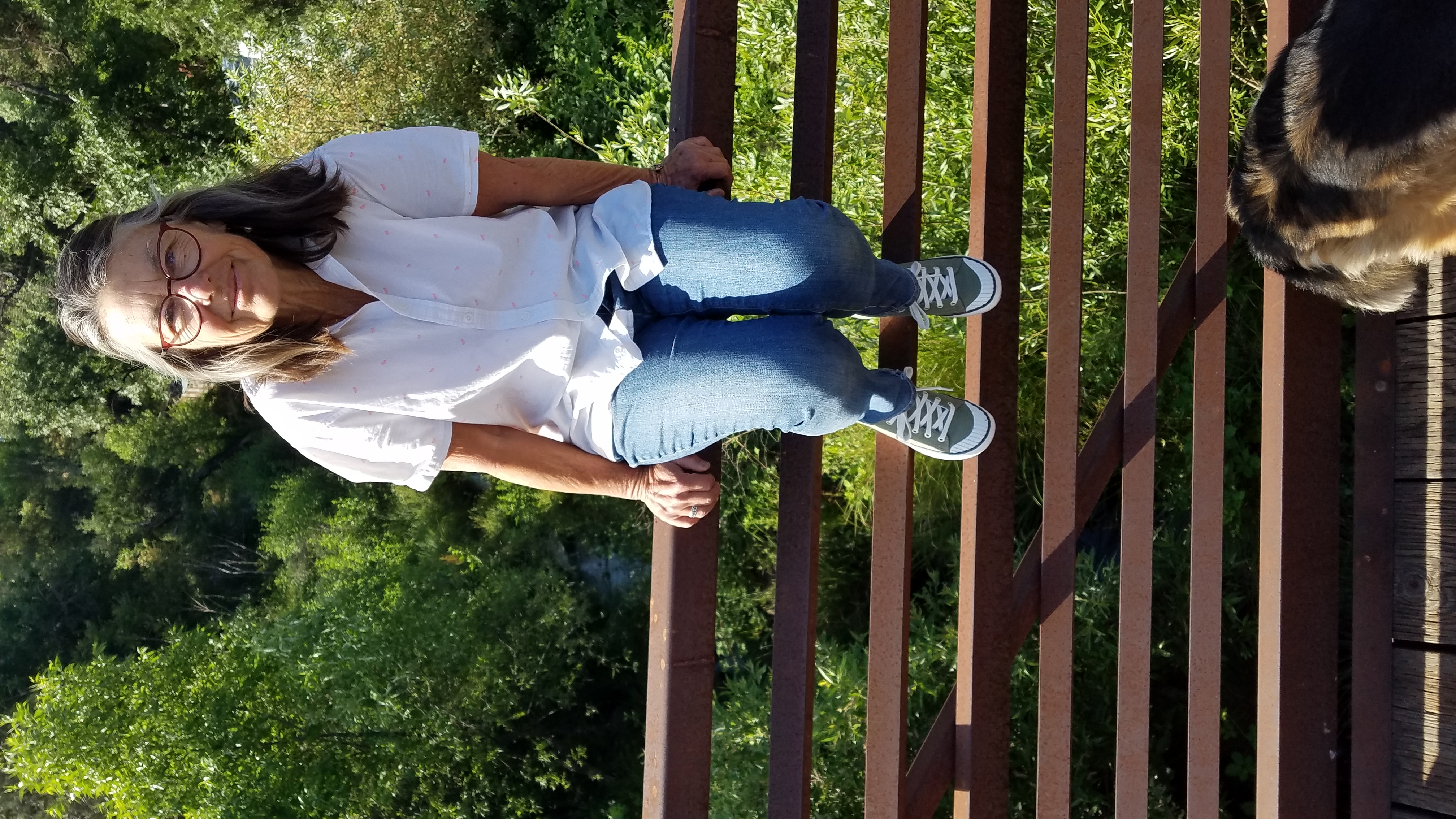 40 Phyllis Becker tmbtp image Older woman sits on rails of a bridge. She is facing the camera and smiling slightly.